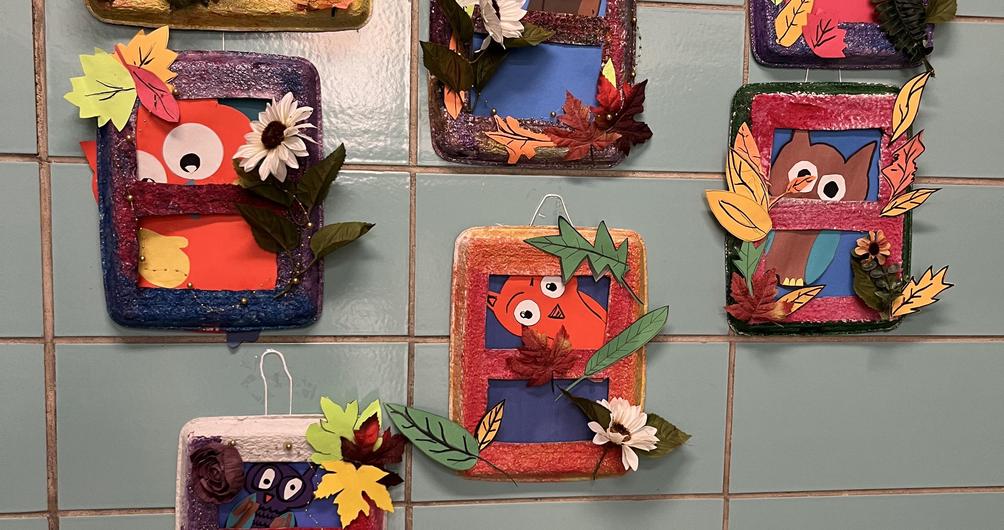 Colorful display of framed animals with autumn leaves and flowers on teal tiles.
