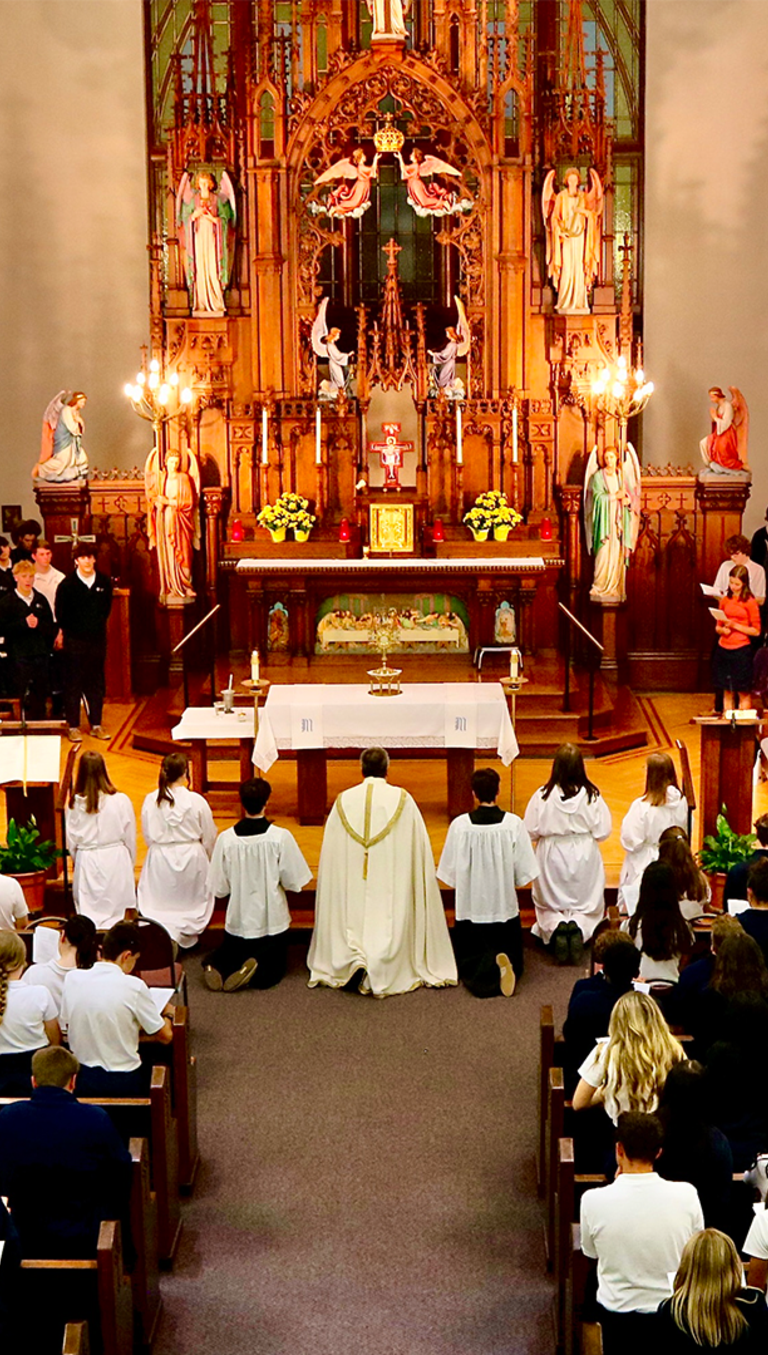 students in the OLSH Chapel with the priest and altar servers at the front of the altar