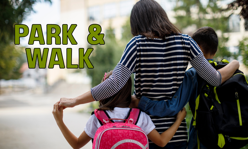 Photo of a mother and two young children carrying backpacks from the back walking to school.