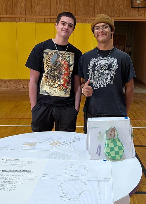 Two students pose, one with a thumbs up