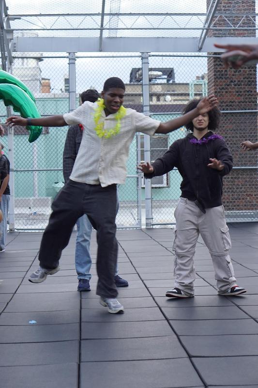 A group of teens enjoying a lively moment with balloons and leis on a rooftop.