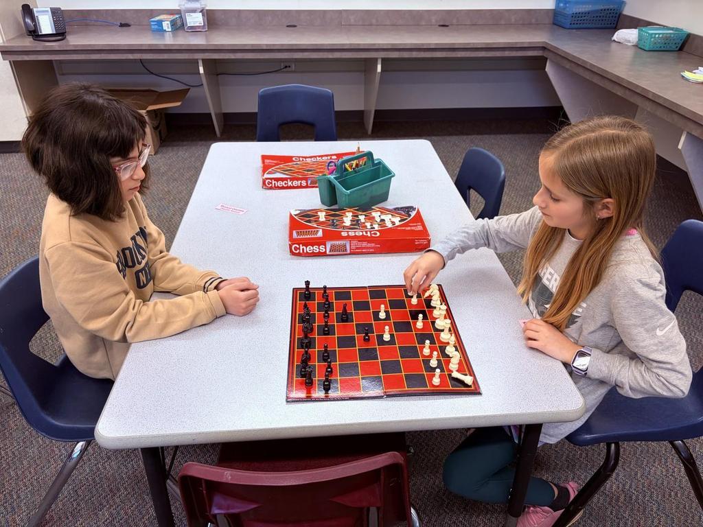 Two elementary students playing chess during chess club after school.