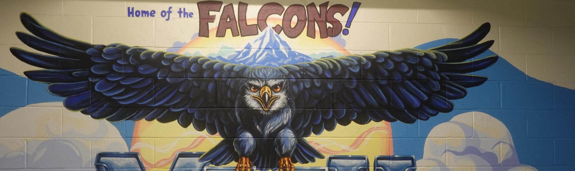 Bright Mott Hall V mural featuring a powerful falcon with outstretched wings perched above the large blue MVH initials, with the phrase ‘Home of the Falcons’ above.