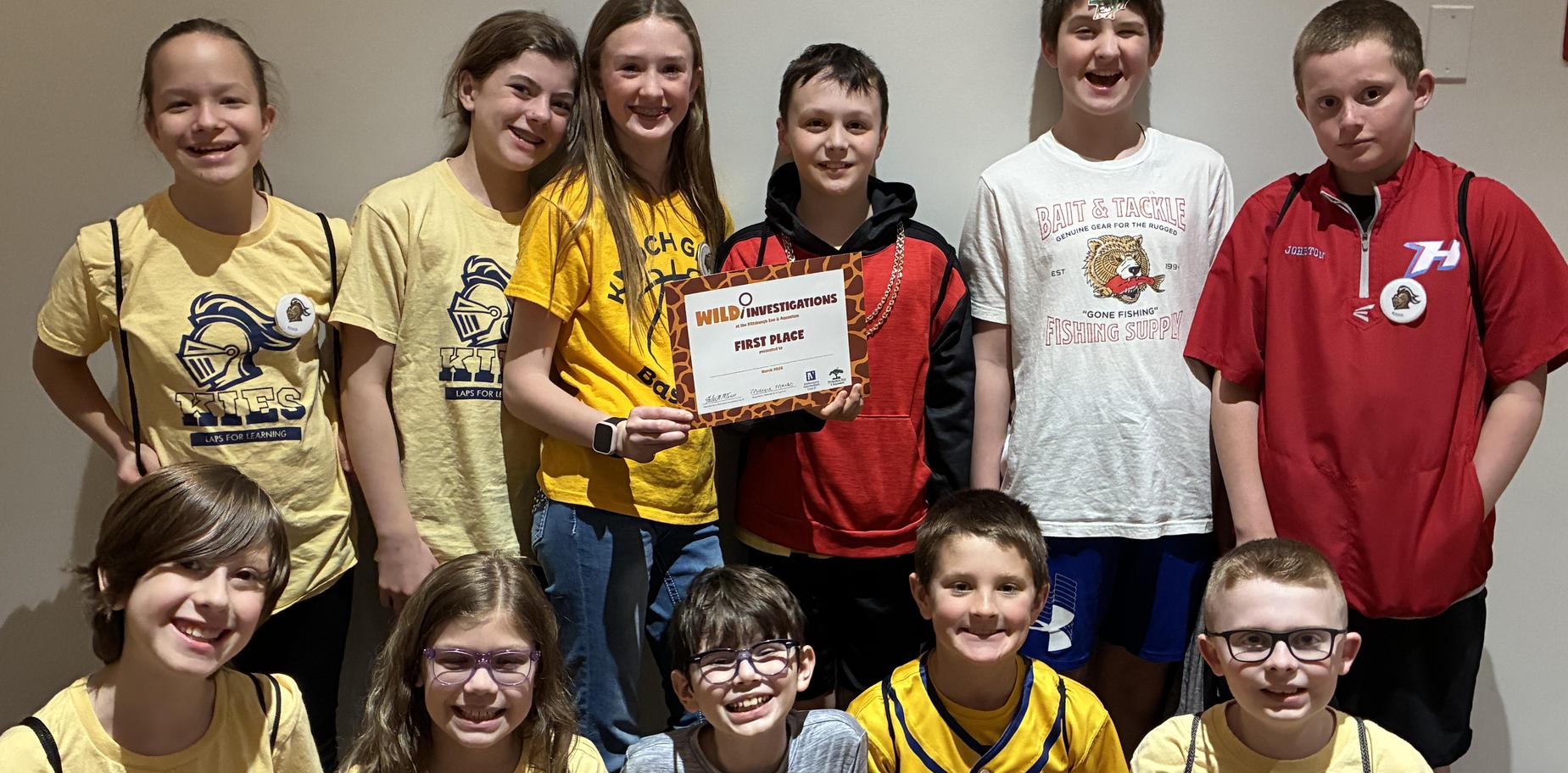 A team of children proudly displays their first-place certificate and poses for a photo.