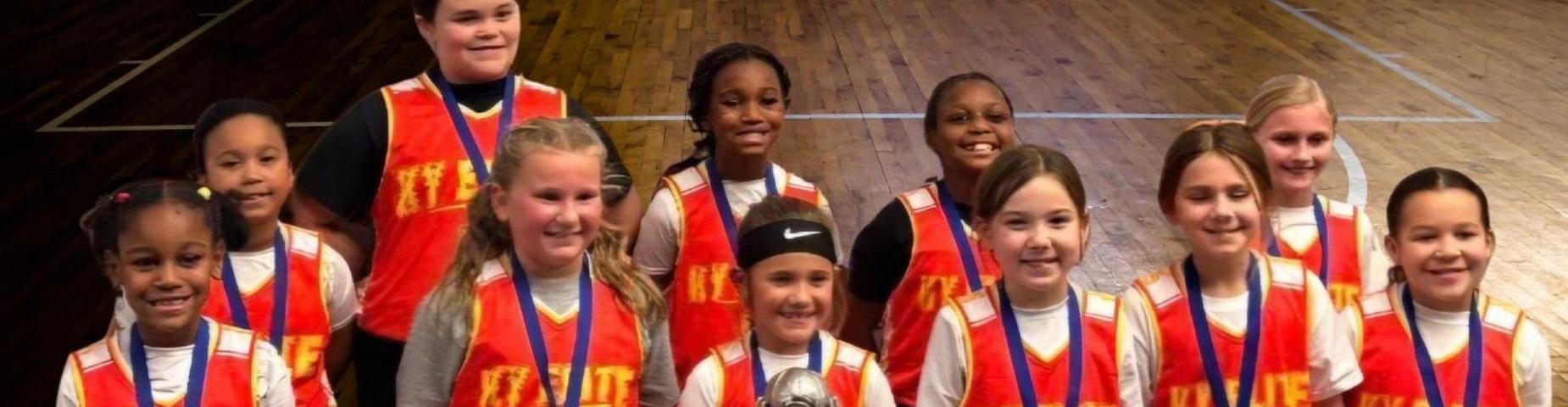 2nd-4th grade girls basketball team holds their trophy