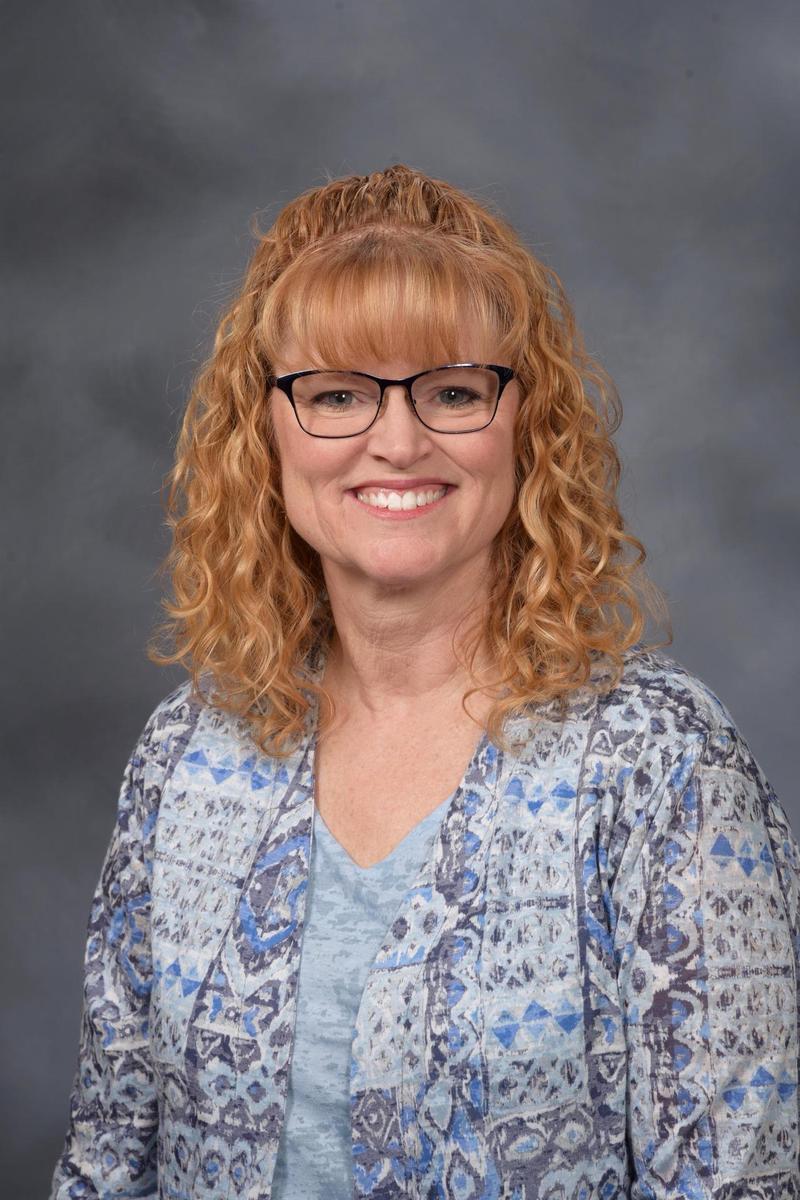 Lara with shoulder length, reddish blonde hair and glasses