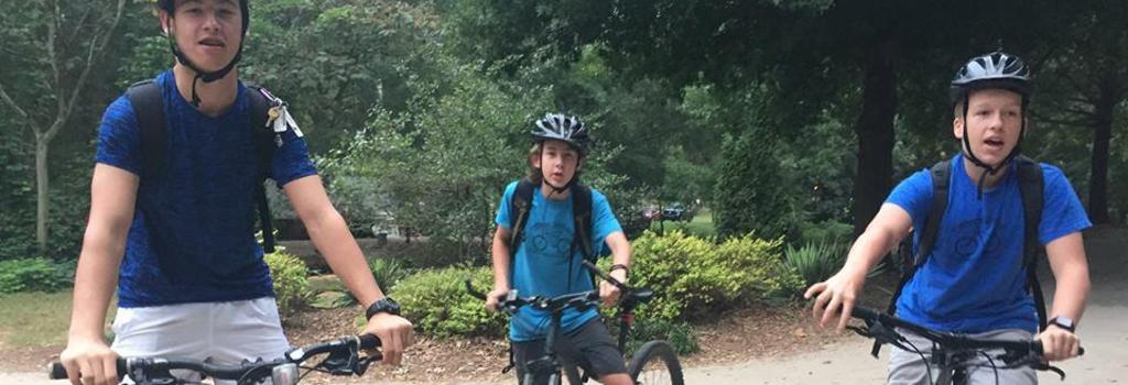 three students wearing helmets on mountain bikes
