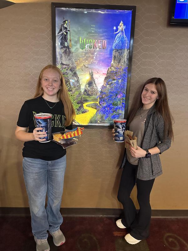 Zoe and Paige standing in front of movie poster