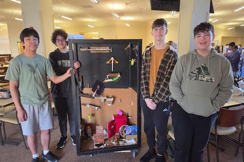 photo of students on the team standing next to their chain reaction machine