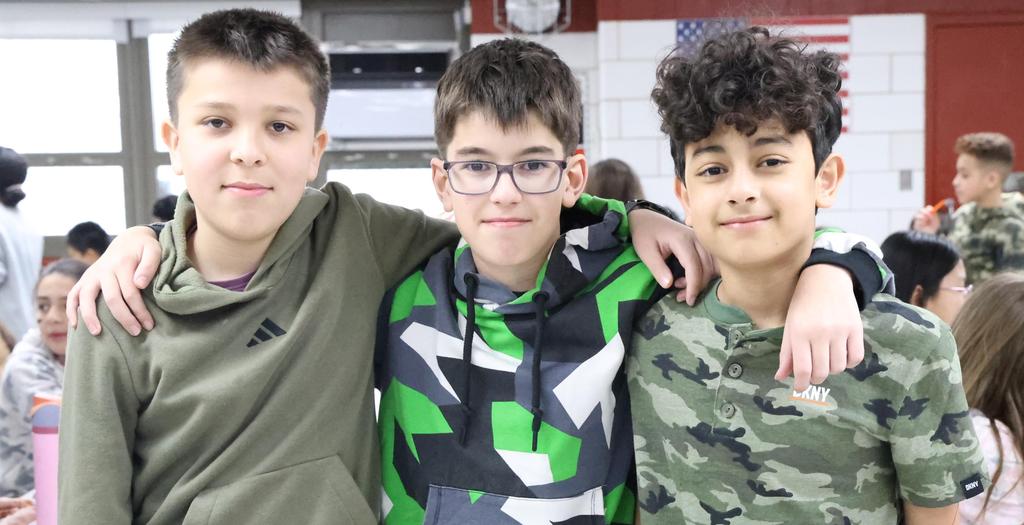 Three boys standing with arms around each other.