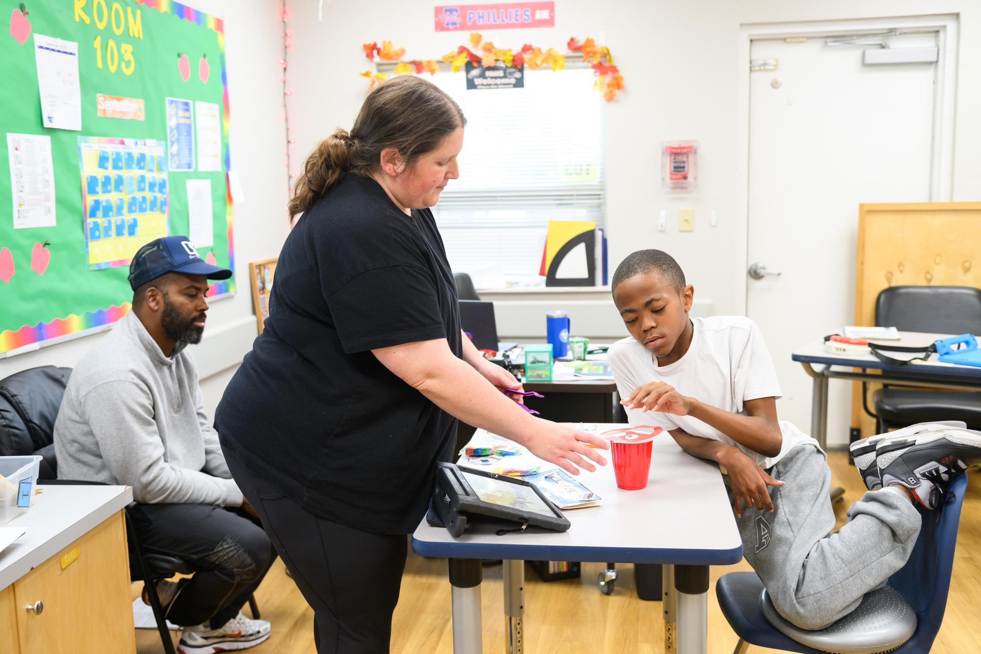 Teacher standing at desk with student.