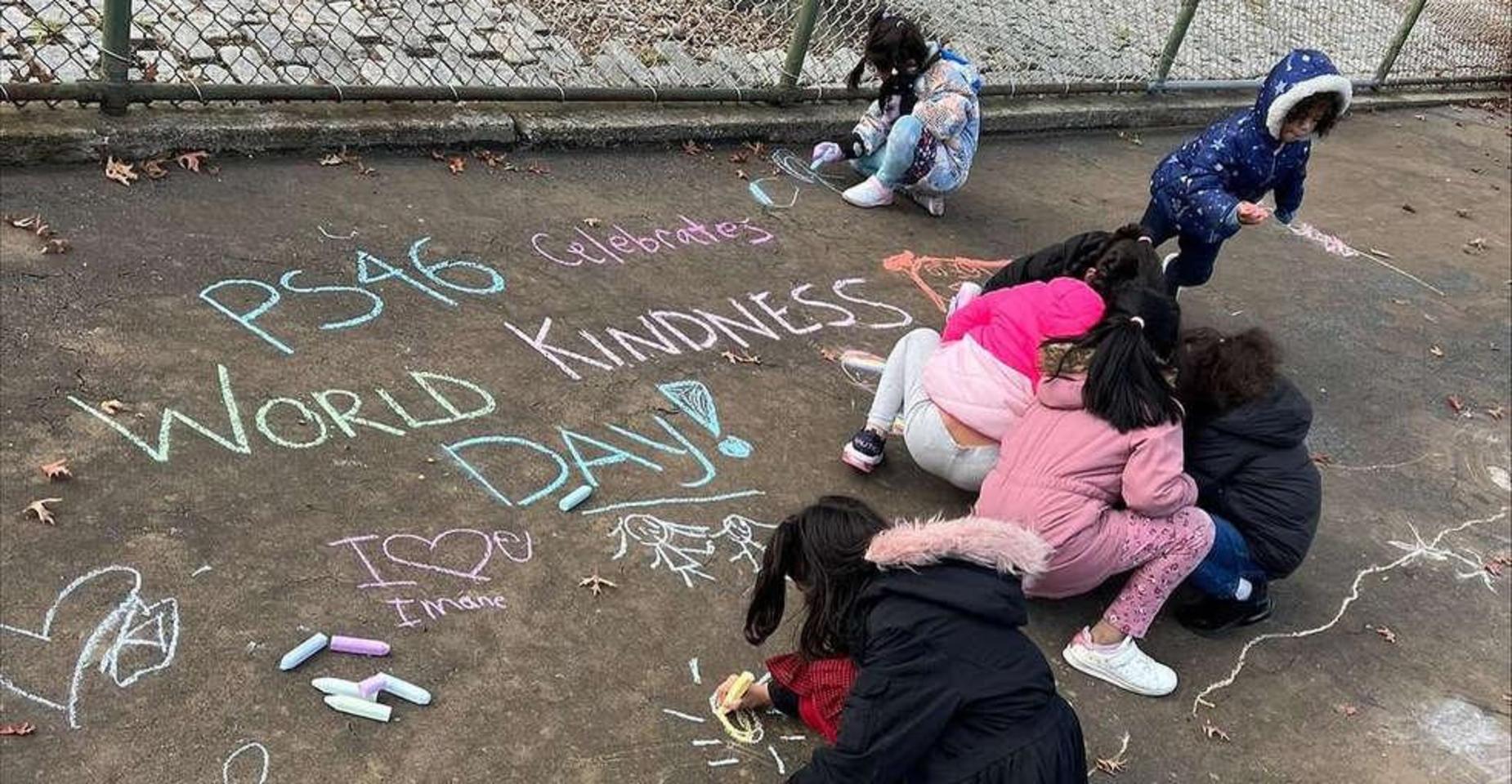 Children using chalk to create drawings and messages for World Kindness Day.