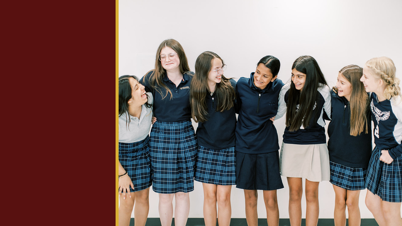 Smiling students in uniform stand arm in arm