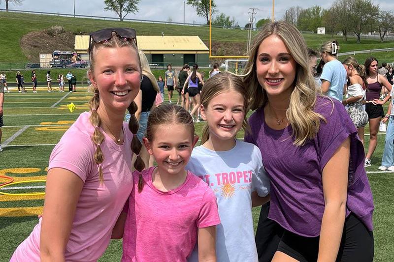 4 students stand together on the football field