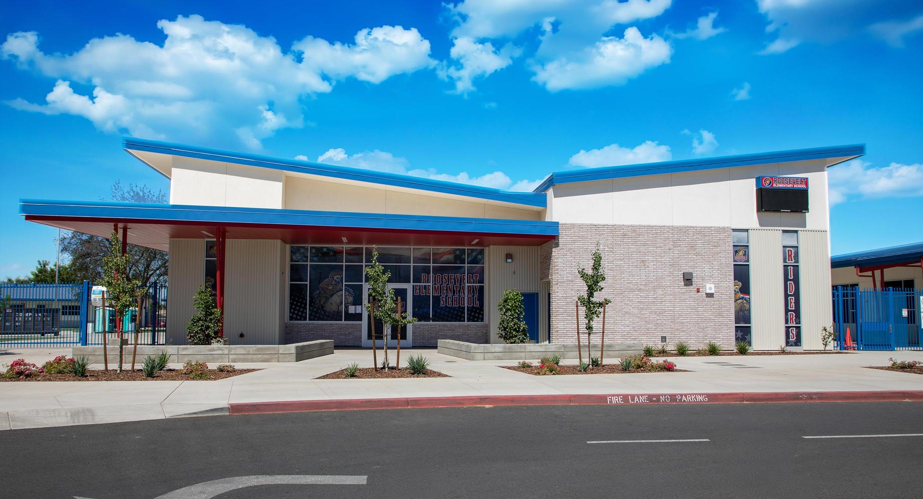 Modern school building with colorful roof and landscaped entrance.