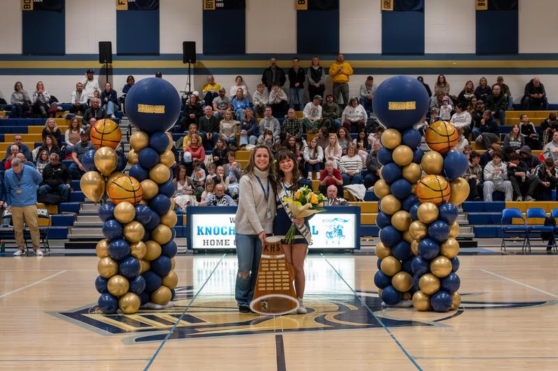 cheerleader holding an award with coach standing beside her