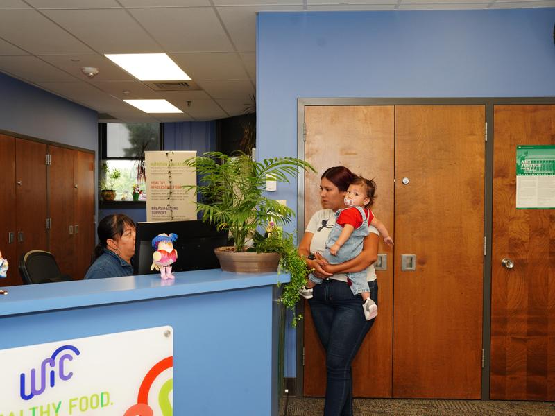 A mother and infant talking with a staff member at the front desk