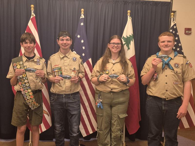 four students dressed in scout attire receiving eagle badge