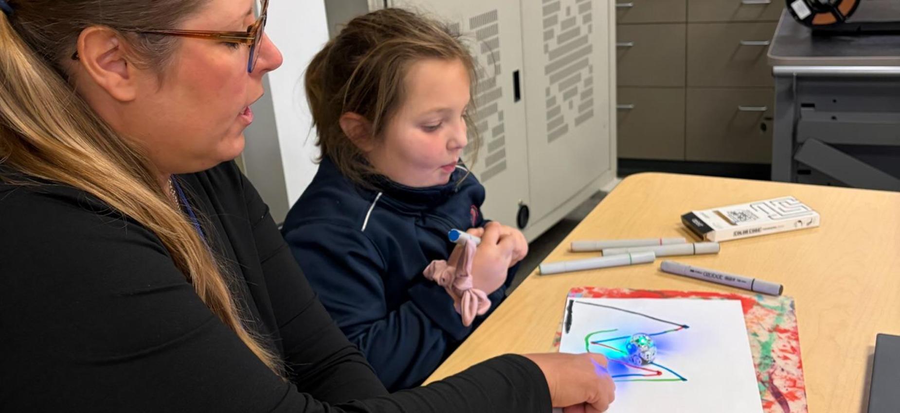 technology teacher working with a student to program ozobot