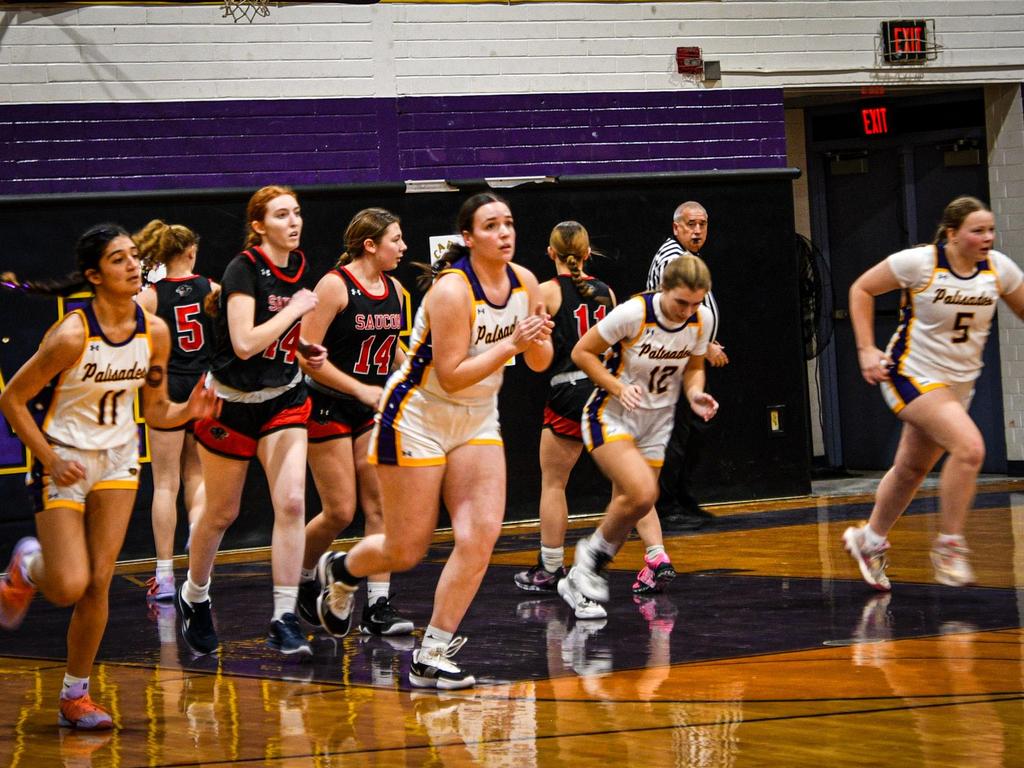 The Girls Basketball team running down the court.