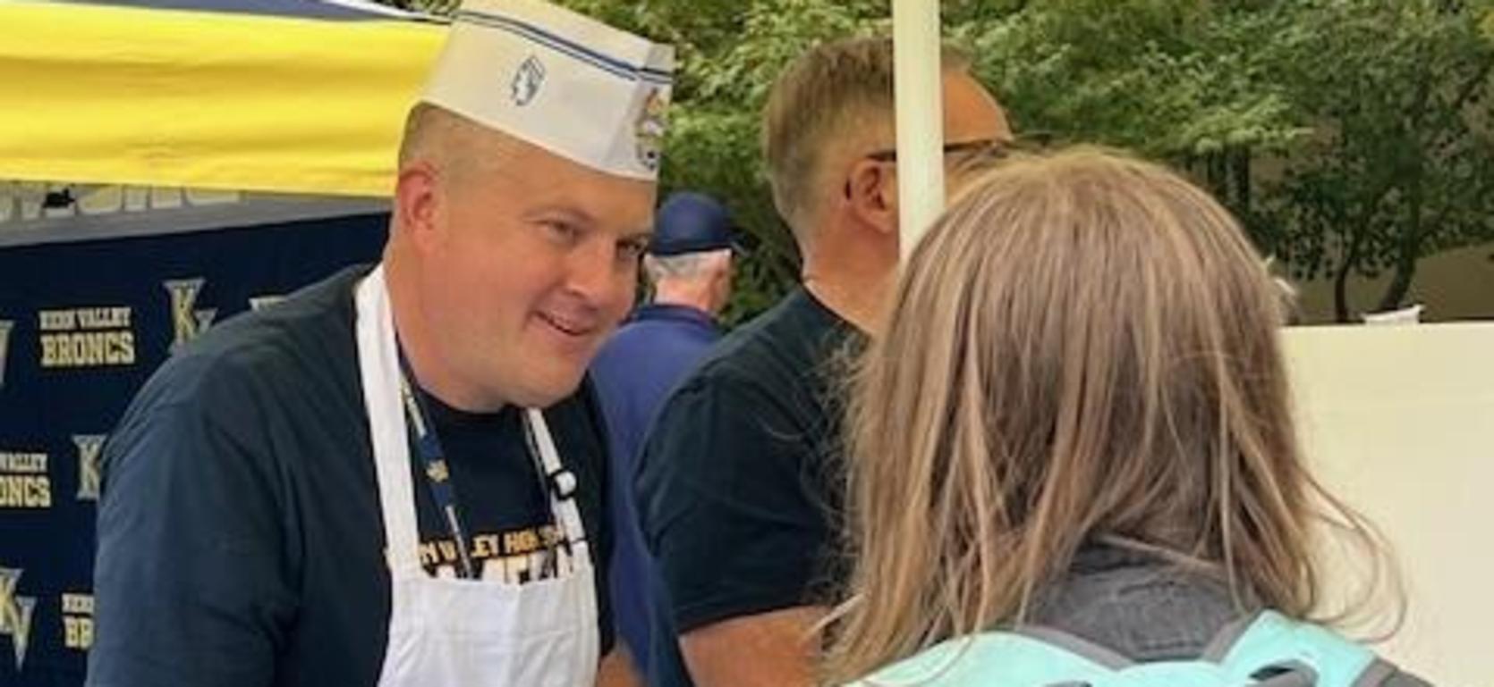 A vendor serves food to a customer at an outdoor event.