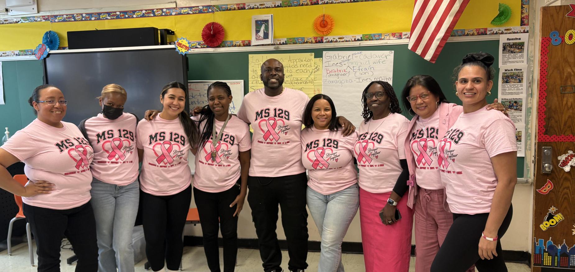 Group of staff members standing in classroom wearing pink MS 119 shirts