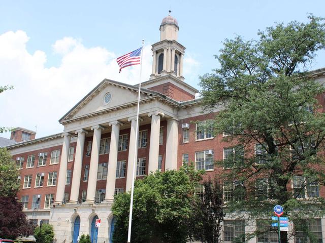 Historic brick building with tall columns and an American flag flying.