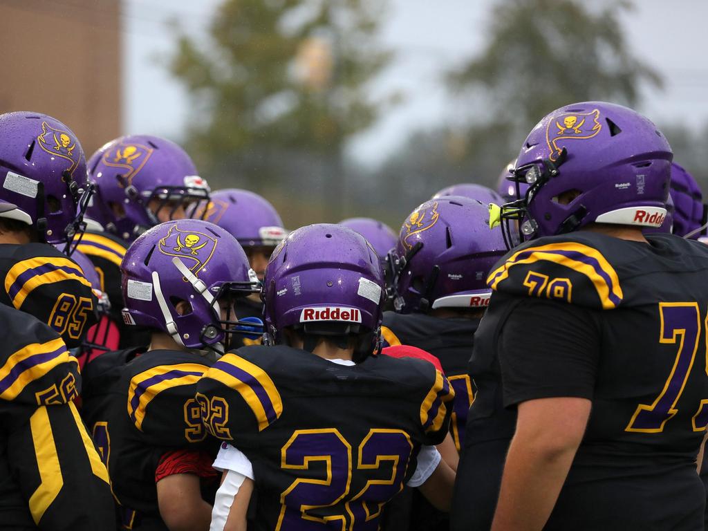 The football team in a huddle on the field.