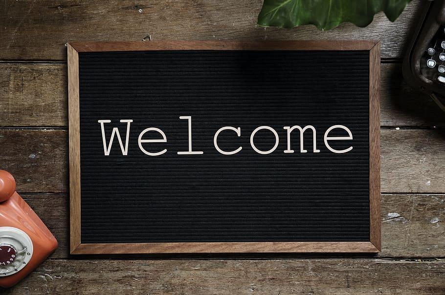 Wooden board displaying the word 'Welcome' in white letters.