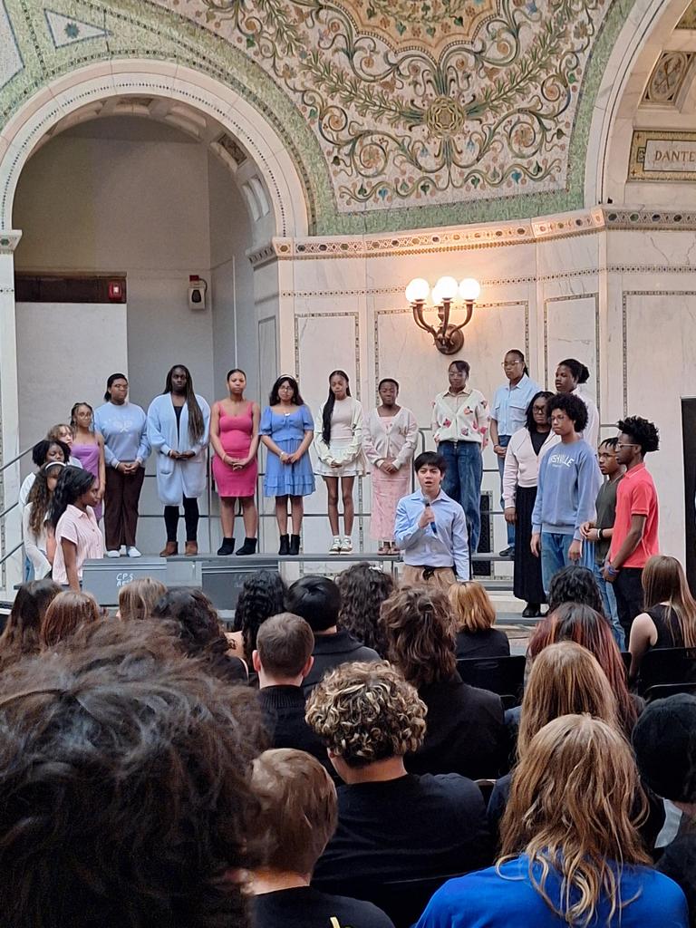 Choir singing in front of seated crowd.