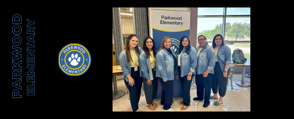 Group of six women in denim jackets posing beside a Parkwood Elementary banner.