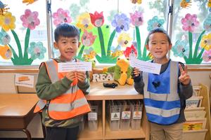 Two student leaders wearing vests hold up signs during classroom rotations.
