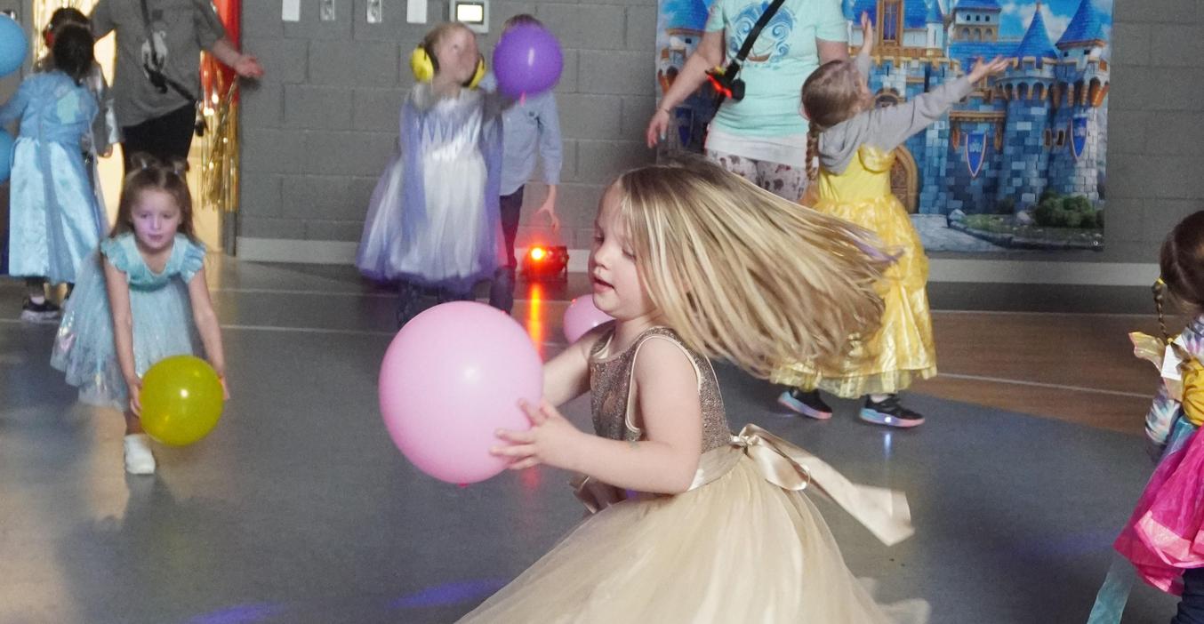 A girl catches a balloon and twirls in her gown at the ECC literacy ball.