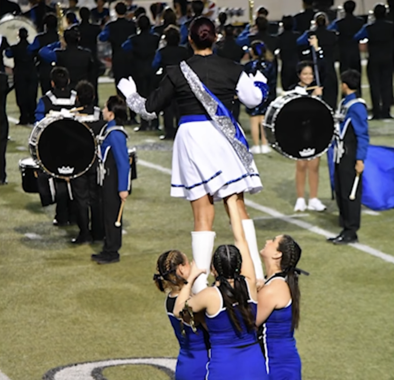 Cheer team holding up a drum major