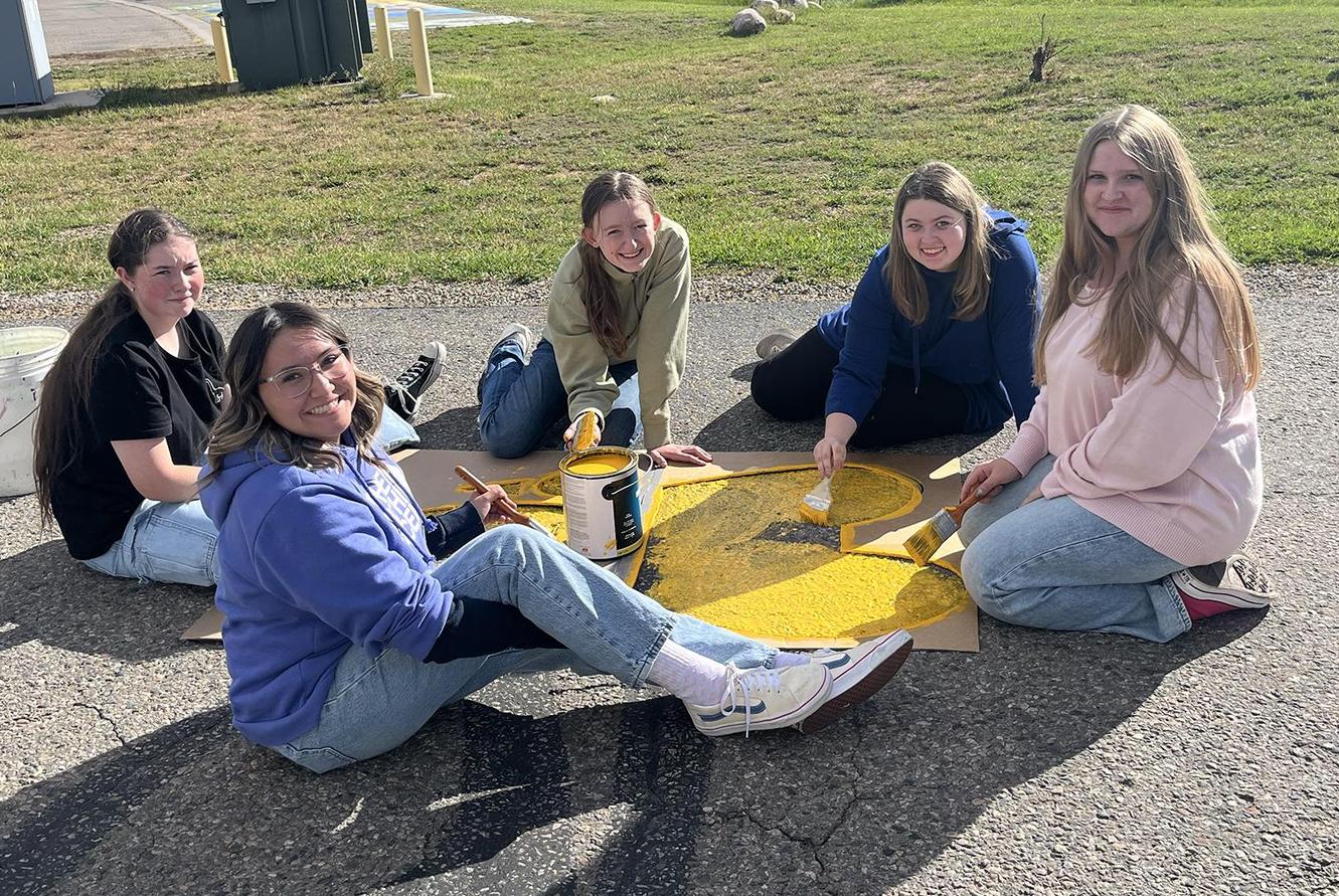 Art students paint a paw print on the drive way