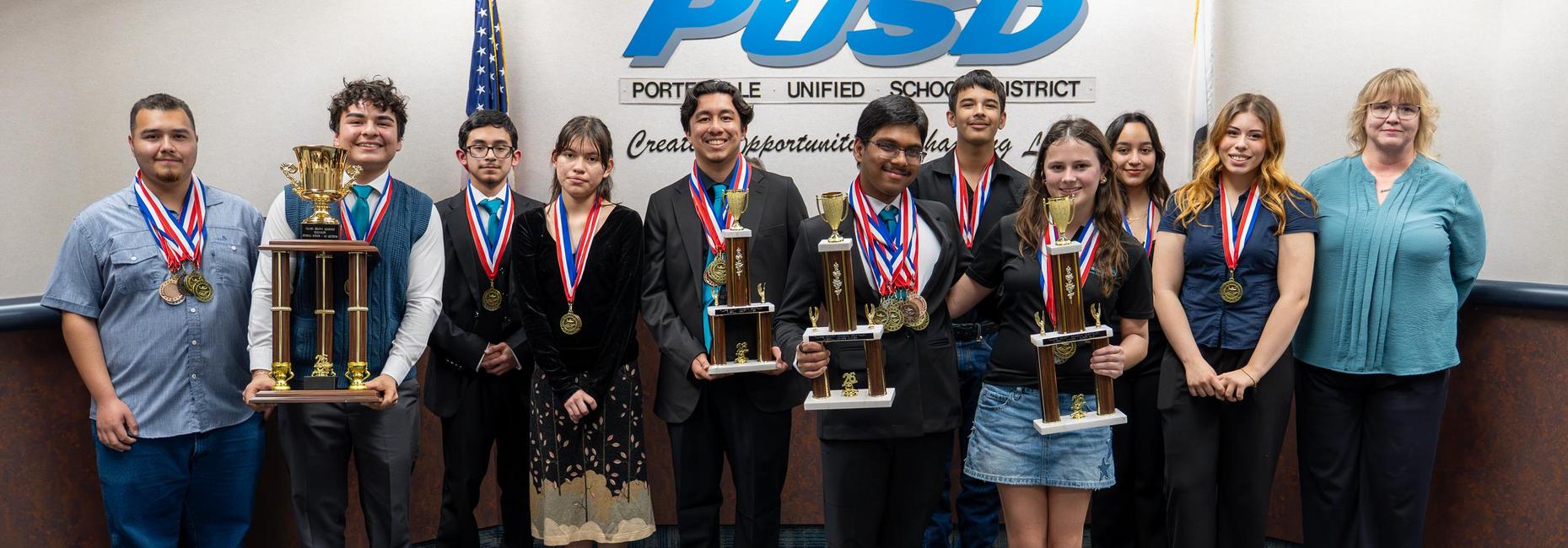 Harmony Magnet Academy Academic Decathlon team holding up trophy in board room
