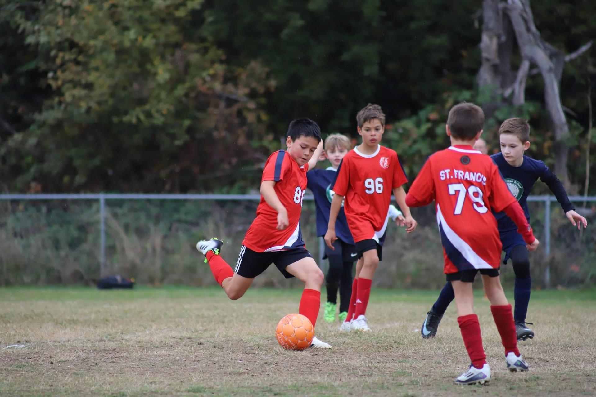 boy kicking soccer ball with teammates