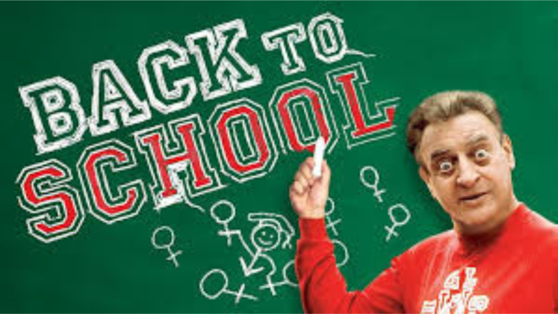 A man pointing at the words 'Back to School' on a green chalkboard.