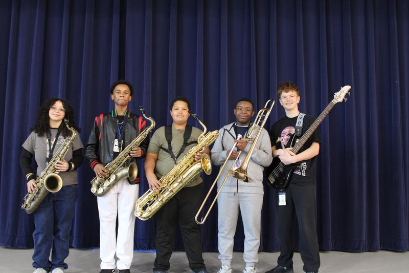 A group of students holding instruments in front of a curtain