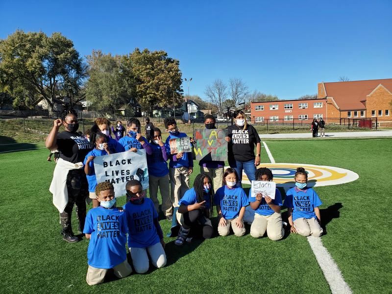 Image shows scholars and their teachers on the soccer field wearing black and blue Black Lives Matter t-shirts