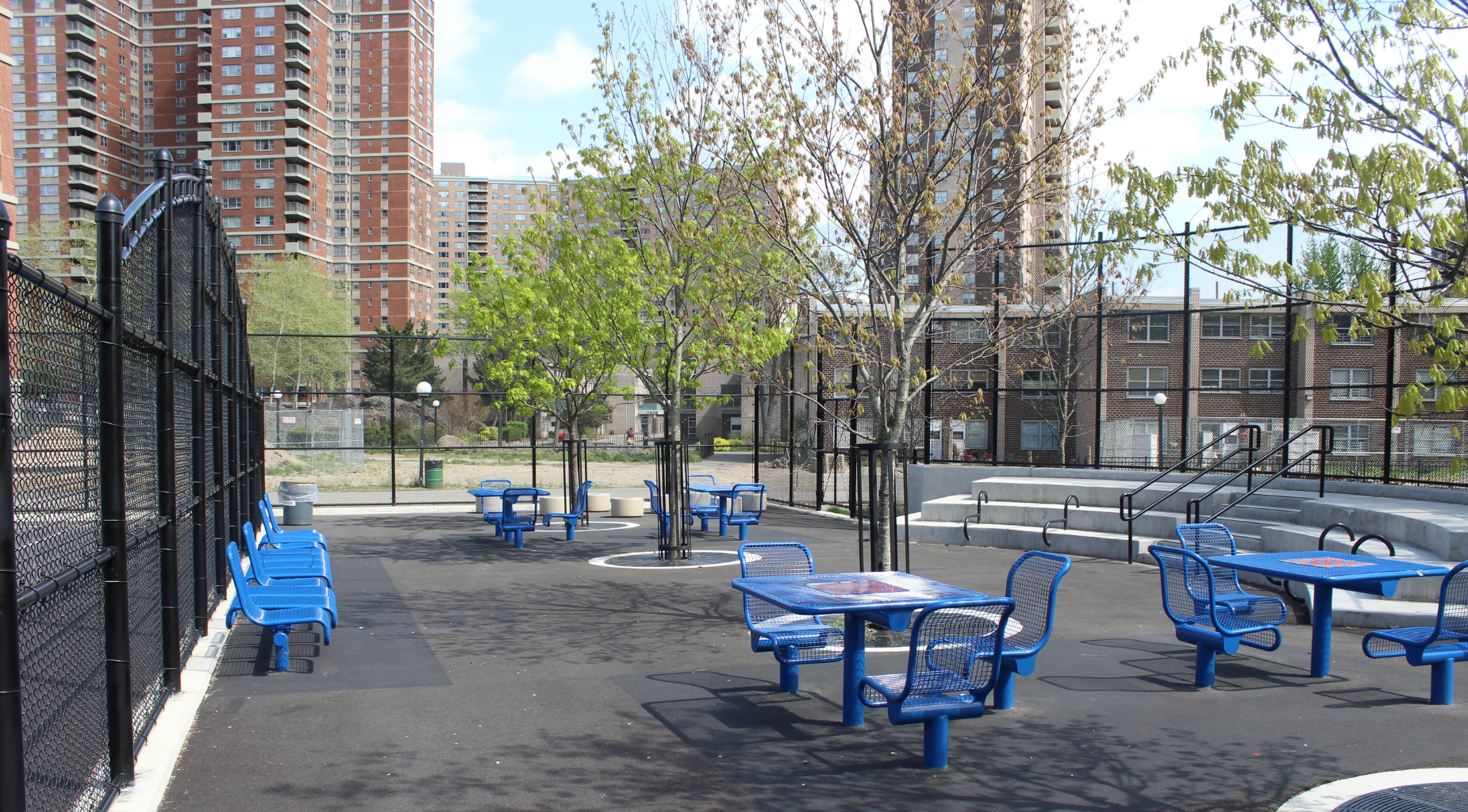 Outdoor area with blue tables and young trees in a recreational space.