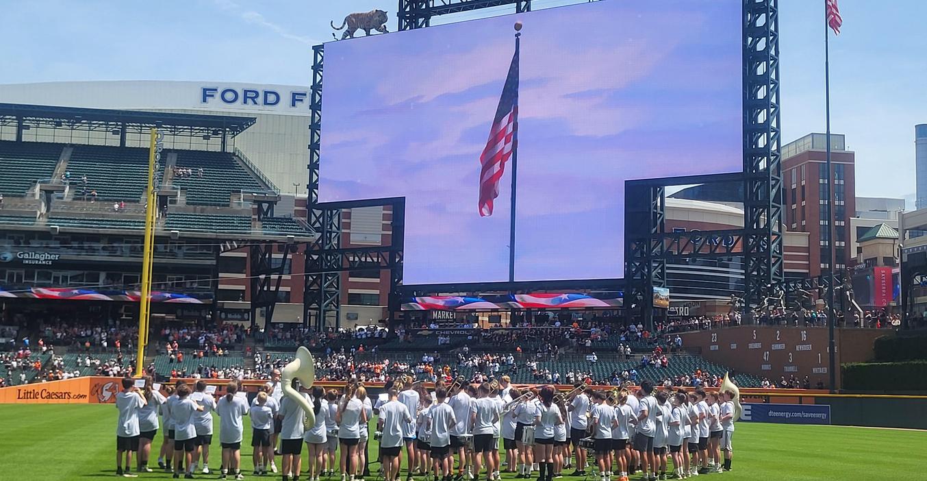 A band performs in front of a large screen displaying an American flag.
