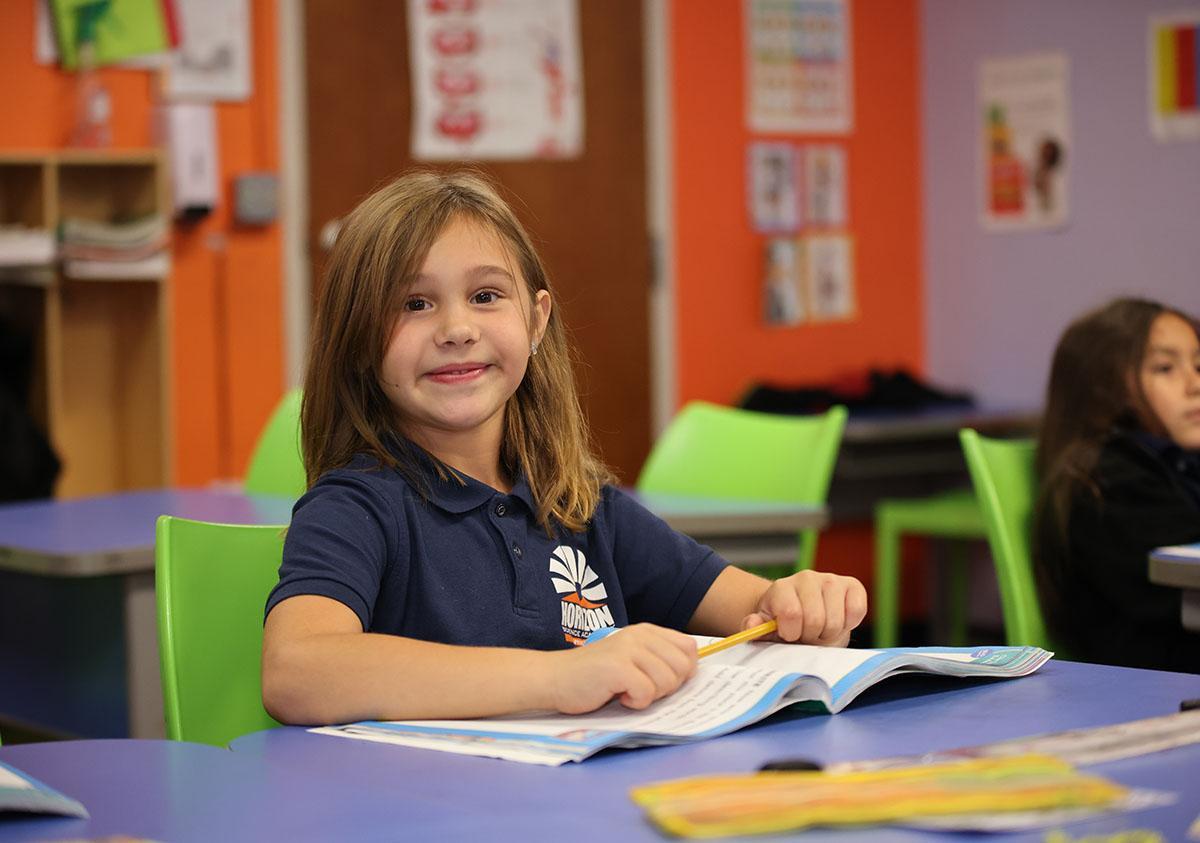 Elementary student smiling and posing together in a classroom.